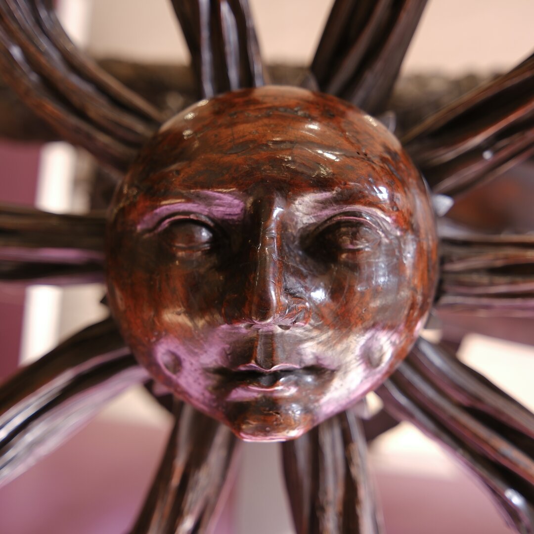 A sun face cast into the hub of an old cart wheel.