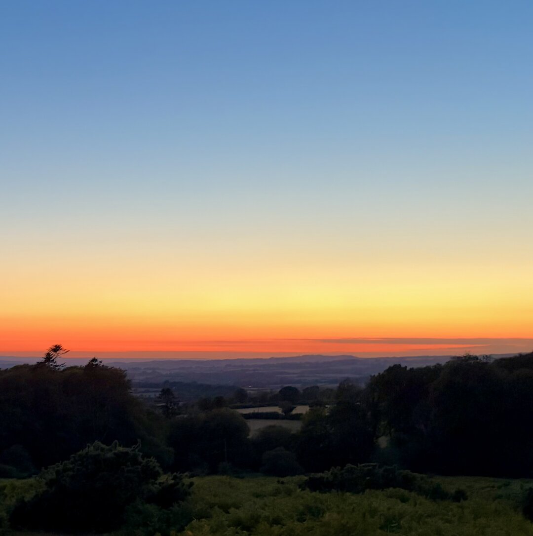Sunset from Pew Tor, an orange band of sky over the darkening moor.
