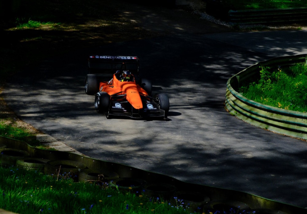 An orange single seater in dappled light at Prescott.